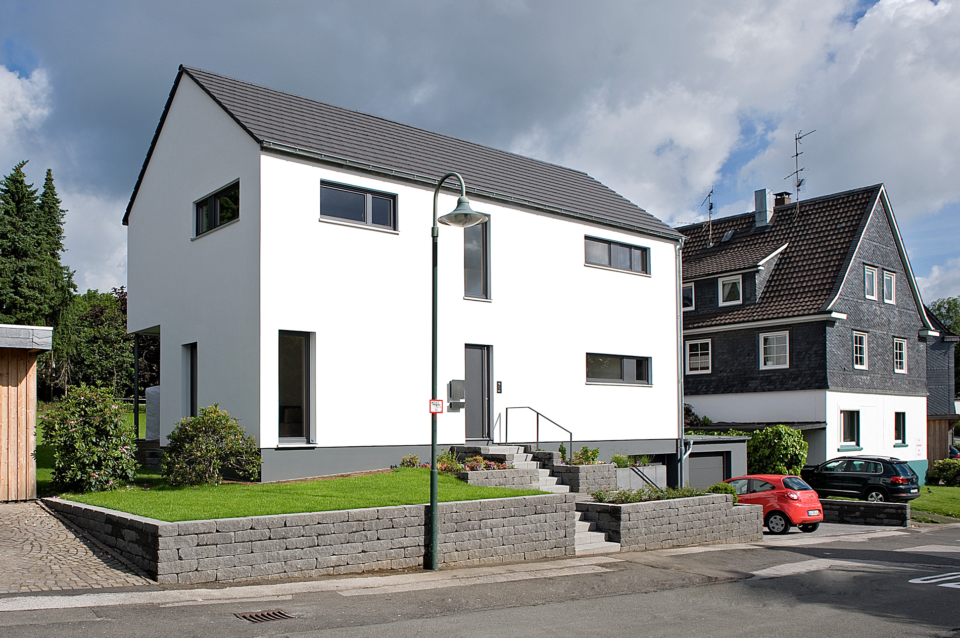 Ein Einfamilienhaus mit Putzfassade mit Anbau mit Rautenschalung von Zultner-Holzbau.